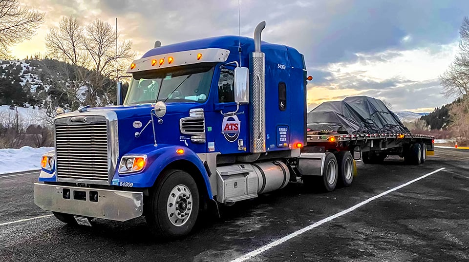 Blue flatbed truck with tarped load