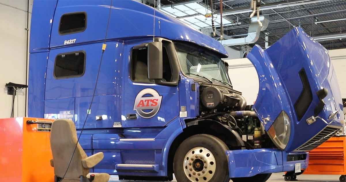 Blue semi truck hood open in maintenance shop