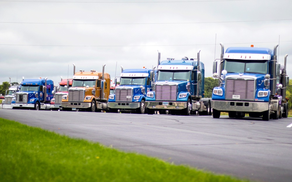 A row of semi trucks in a parking lot.