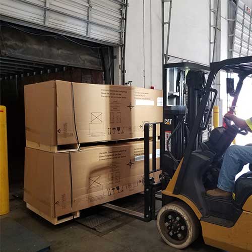 forklift loading pallets into trailer at loading dock
