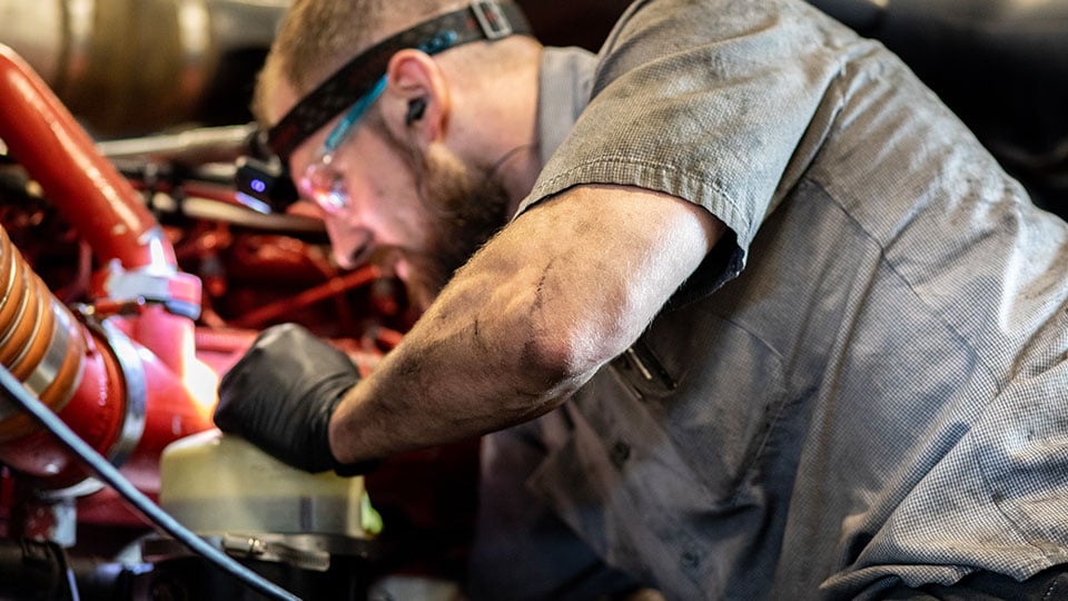 Diesel-mechanic-leaning-over-semi-truck-engine