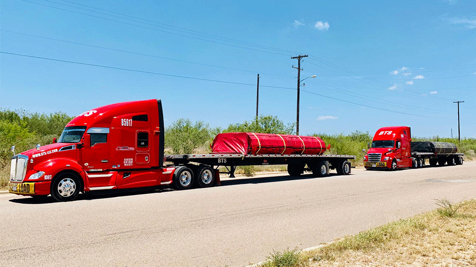 Two red semis with flatbed trailers