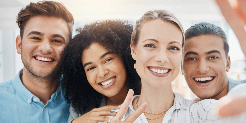 Team of four coworkers taking a selfie together.